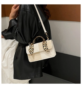 Detail of minimalist rectangular crossbody bag with leopard print silk scarf on handle