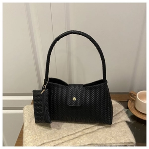 Close-up of black woven leather texture with gold magnetic clasp and matching mini pouch