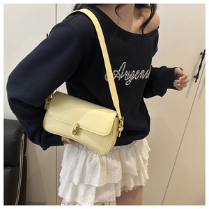 Chic cream yellow underarm bag with gold twist lock shown on a model's shoulder