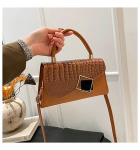 Close-up of brown crocodile texture flap bag with a gold-trimmed geometric buckle