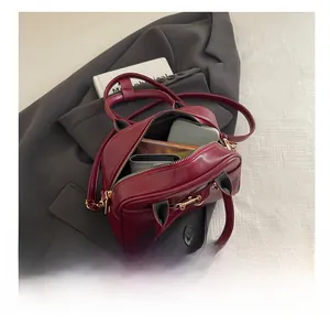 Deep red leather Boston bag interior showing capacity for phone, wallet and notebook