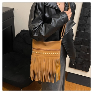 Detail view of brown tassel shoulder bag with golden studs on a black leather jacket