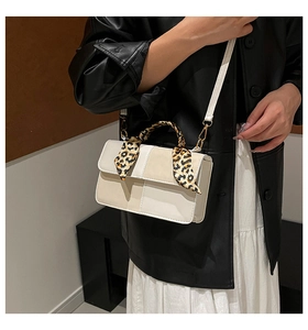Detail of a chic cream crossbody bag with a leopard print scarf on the handle