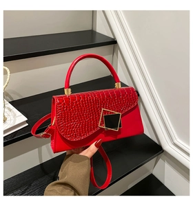 Detail of red croc-embossed leather handbag with geometric metal buckle and top handle