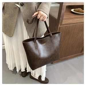 Détail d'un sac cabas en cuir marron foncé avec texte Fashion Bags doré et décor élégant
