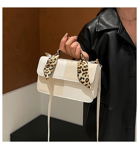 Close-up of beige crossbody bag featuring leopard print scarf and gold hardware