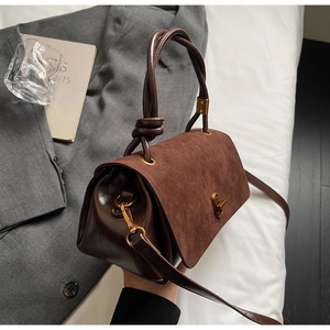 Detail of vintage brown suede satchel with knot handle and antique bronze twist lock clasp