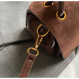 Detailed close-up of dark brown suede stitching and premium gold metal hardware hooks