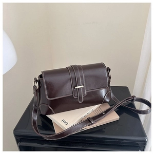 Dettaglio borsa baguette marrone vintage con cuciture a contrasto e fibbia dorata