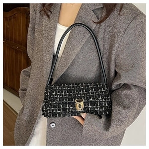 Detail view of black and white tweed baguette bag with gold twist lock on model