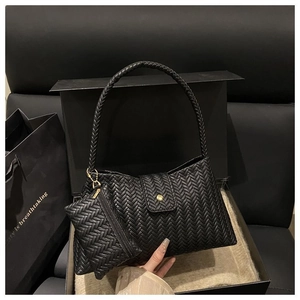 Close-up of black woven shoulder bag with metal buckle and matching coin purse detail