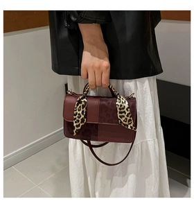 Detail of red faux leather handbag with leopard print scarf wrap on the handle