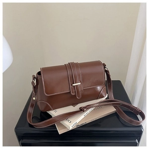 Dettaglio della borsa in pelle marrone con cuciture bianche e fibbia dorata