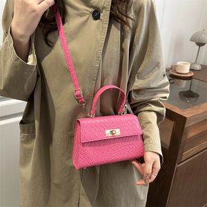 Petit sac à main carré tressé rose avec poignée et fermoir tournant doré sur mannequin