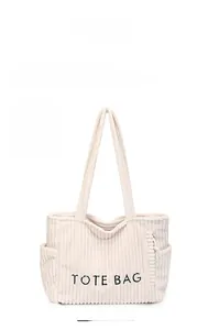 Detail einer beigen Cord-Einkaufstasche mit schwarzer Bestickung und seitlicher Tasche