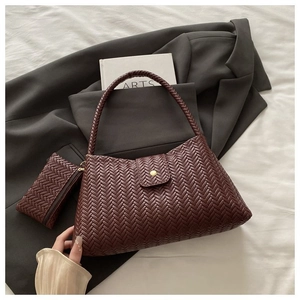 Close-up of woven dark brown leather tote and matching zipper pouch on a grey blazer