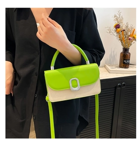 Détail du sac contrasté vert et beige avec anneau argenté porté par le modèle