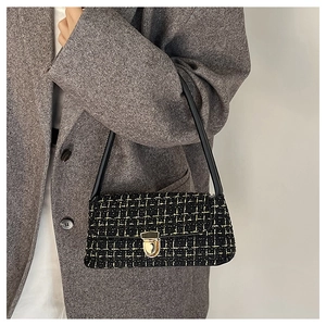 Detail of tweed underarm bag with gold clasp shown on a model in a grey blazer