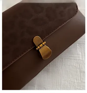 Detail of vintage brown shoulder bag featuring leopard print flap and gold metal buckle