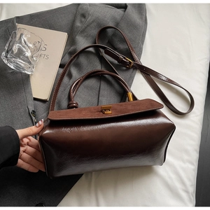 Detail of suede and leather textures on dark brown crossbody bag with metal lock