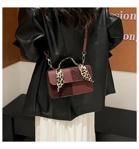 Detail of burgundy crossbody bag with leopard print handle scarf and gold hardware