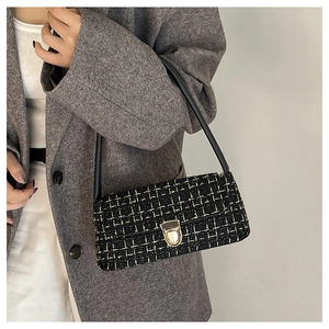 Detail of tweed underarm bag with gold lock and textured black and yellow weave