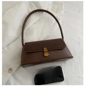 Detail of a dark brown leather handbag with gold buckle and size reference to a phone