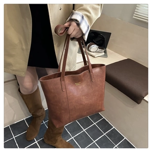 Gros plan sur un sac cabas marron vintage avec texte doré dans un décor urbain chic