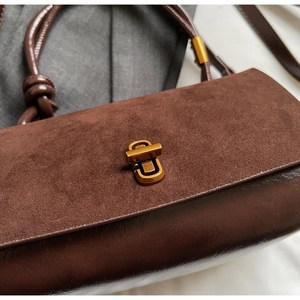Detail of dark brown suede and leather stitching with a vintage gold metal twist lock