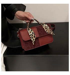 Detail of burgundy crossbody bag with leopard print scarf handle and gold hardware
