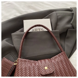 Detail of burgundy woven leather shoulder bag with matching mini pouch on casual background