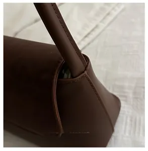 Close-up of high-quality brown leather bag showing meticulous stitching and strap connection