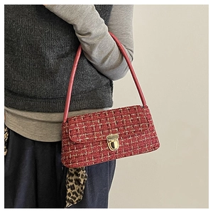 Detail of red tweed underarm bag with gold twist lock and woven texture on a model