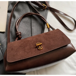 Detail view of brown suede and leather crossbody bag with vintage golden twist lock
