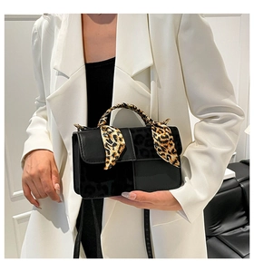 Detail of black leather handbag with leopard print splice and silk scarf handle accent