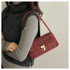 Detail of red tweed underarm bag featuring a classic gold-tone metal clasp closure