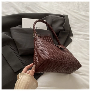 Close-up of a woven dark brown underarm bag with a matching inner pouch and gold zipper