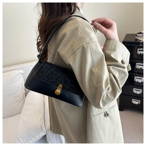 Detail of black leather underarm bag with leopard print flap and vintage gold buckle