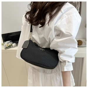 Détail du sac sous le bras en PU noir avec texture gaufrée diagonale et lettrage doré