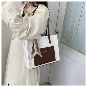 Detail of elegant two-tone tote bag with decorative silk scarf and fashion bag text
