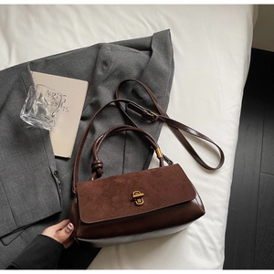 Detail of coffee suede and glossy leather splicing on vintage handbag with gold clasp