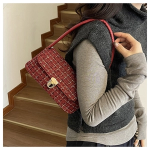 Close-up of burgundy tweed underarm bag with gold metallic threads and turn-lock