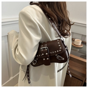 Detailed side view of dark brown leather shoulder bag with silver rivets and metal buckle
