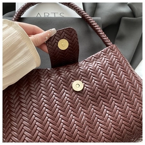 Detail of burgundy woven shoulder bag with gold magnetic clasp and luxury texture