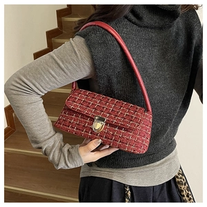 Detail of red tweed shoulder bag featuring a vintage gold clasp and leather strap