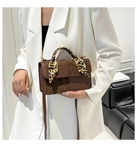 Detail of brown rectangular handbag with leopard print scarf handle and smooth leather texture