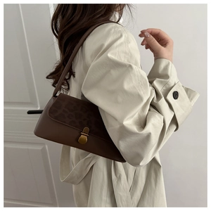 Detail of vintage brown leather underarm bag with leopard print flap and gold metal buckle