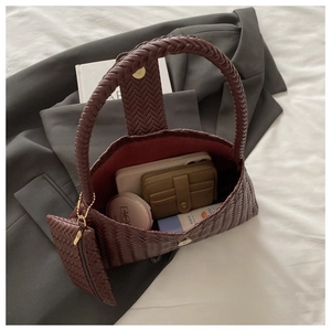 Detail view of woven leather crescent bag interior with matching mini pouch and daily items