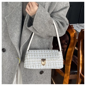 Detail of white tweed shoulder bag with golden metallic clasp and woven texture finish