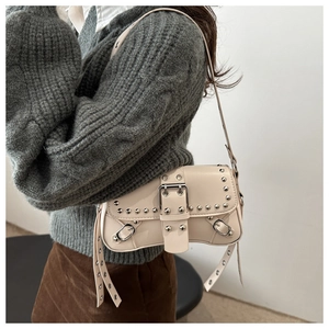 Detail of off-white Y2K baguette bag with silver studs and adjustable shoulder strap